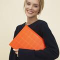 a-cheerful-woman-smiles-while-holding-an-orange-folder-against-a-neutral-background-TC7iVNsn3LcWUdiLXSH-qw