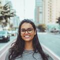 a-young-woman-with-glasses-smiling-on-a-city-street-embracing-urban-lifestyle-HkNpwKAJtaUTDXwETlHDZw